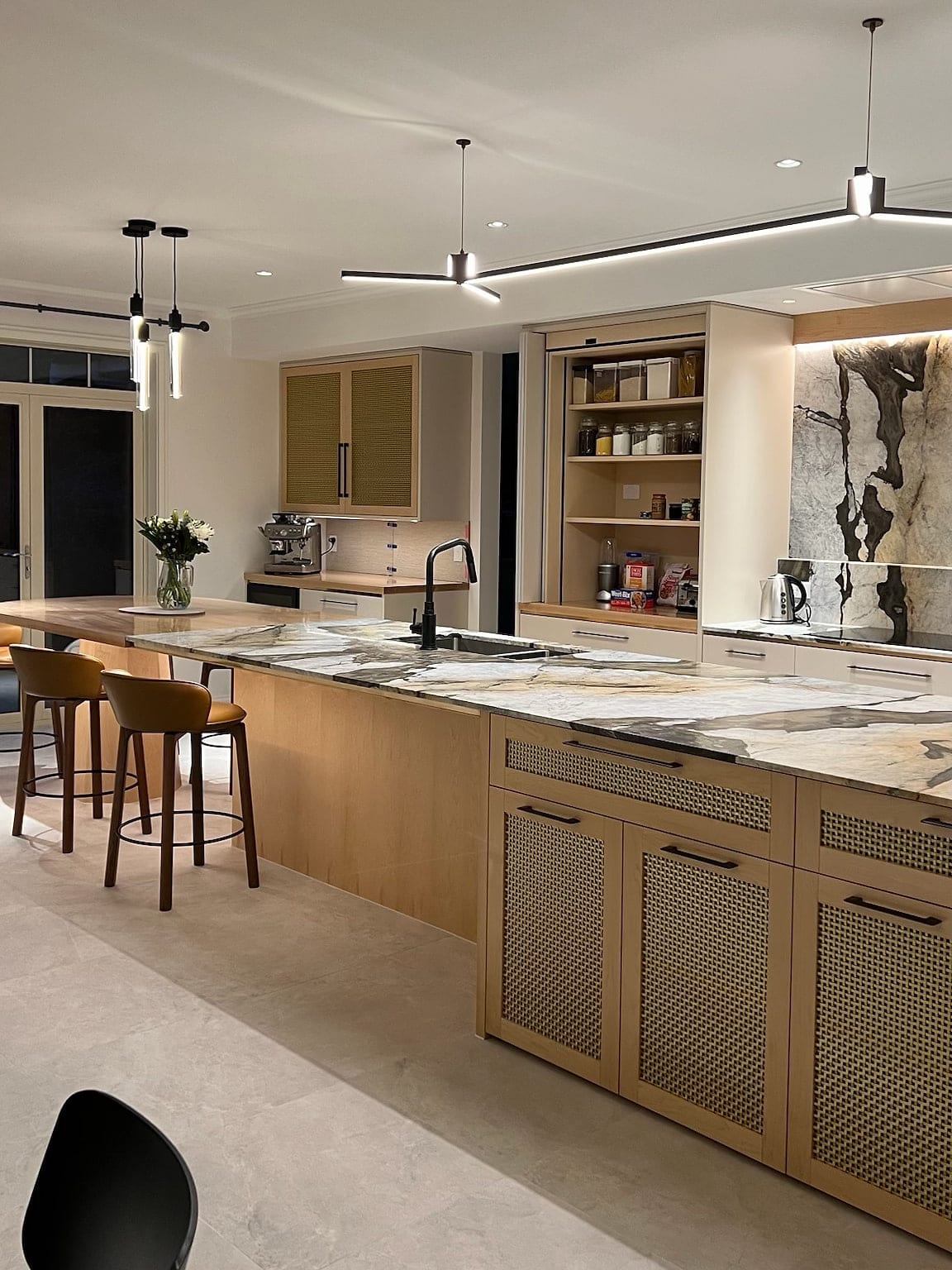 A renovated Lake Hāwea kitchen seen along the island, with the 600×600 porcelain floor running unbroken past the cabinetry and on through the doorway.